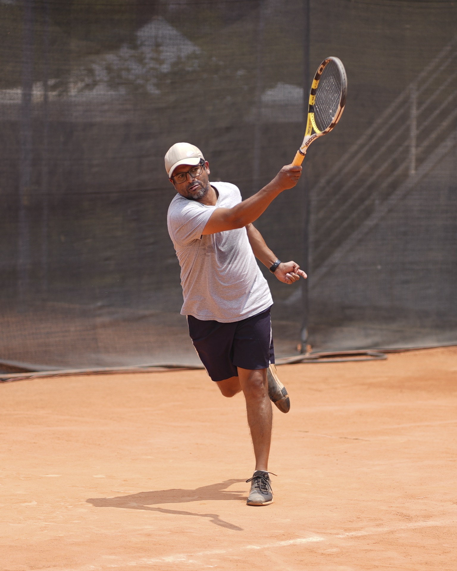 Adult player finishing a forehand on the clay court