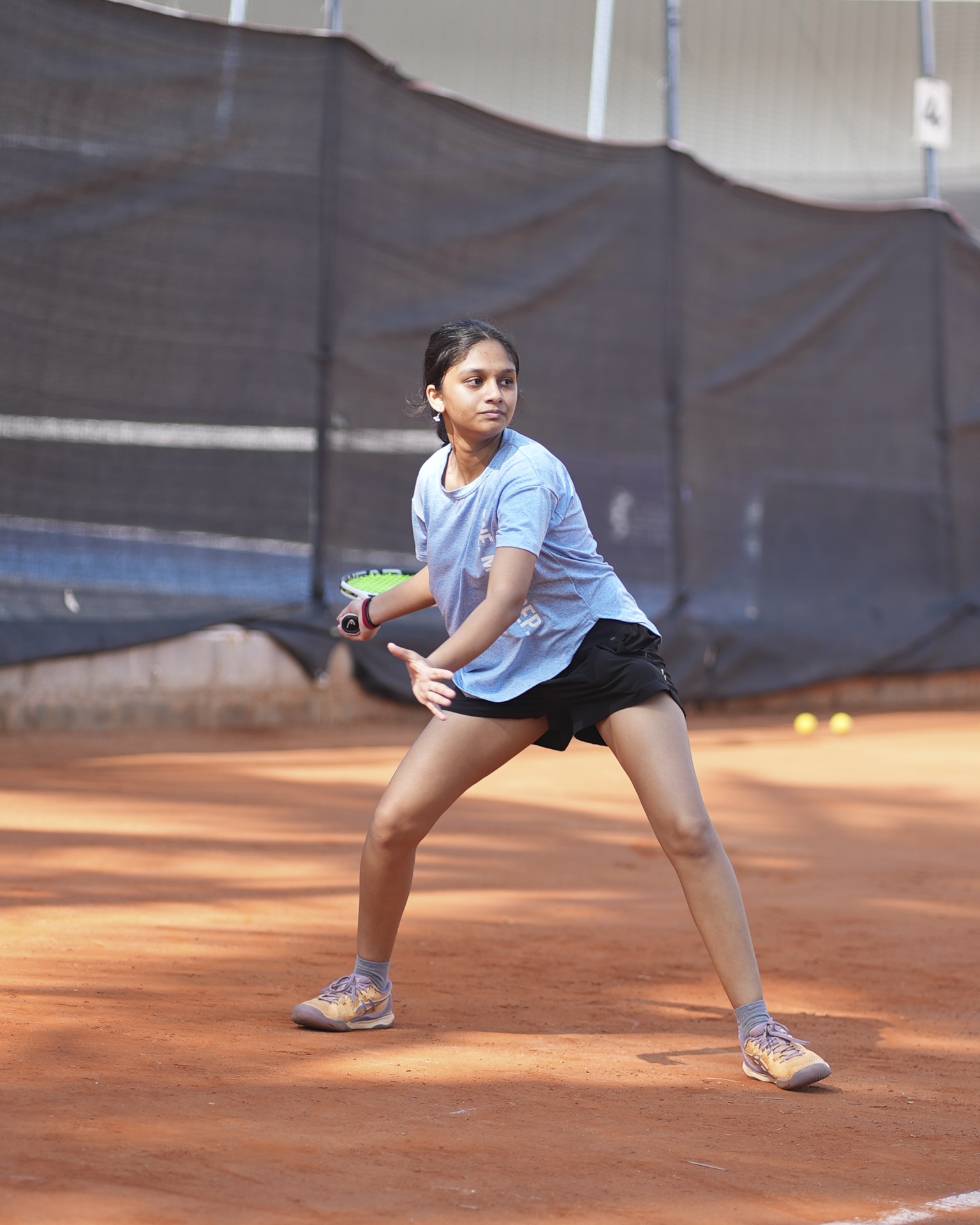Junior Development player striking a forehand on the clay court
